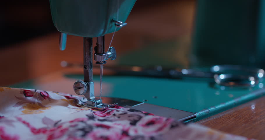 Close-up shots of vintage sewing machines in use, fabric being stitched, threaded and adjusted by hand under soft cinematic lighting. Some clips include slow motion and detailed mechanisms.