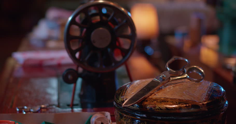 Close-up shots of vintage sewing machines in use, fabric being stitched, threaded and adjusted by hand under soft cinematic lighting. Some clips include slow motion and detailed mechanisms.