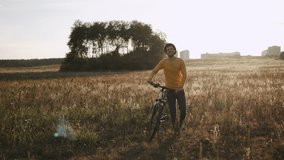 Happy Caucasian man walking with bicycle in hands across field in rays of sun. Evening exciting bike ride in nature through picturesque places. Rest from bustle of city. - Powered by Shutterstock - Get 15% off with code: PIKWIZARD15
