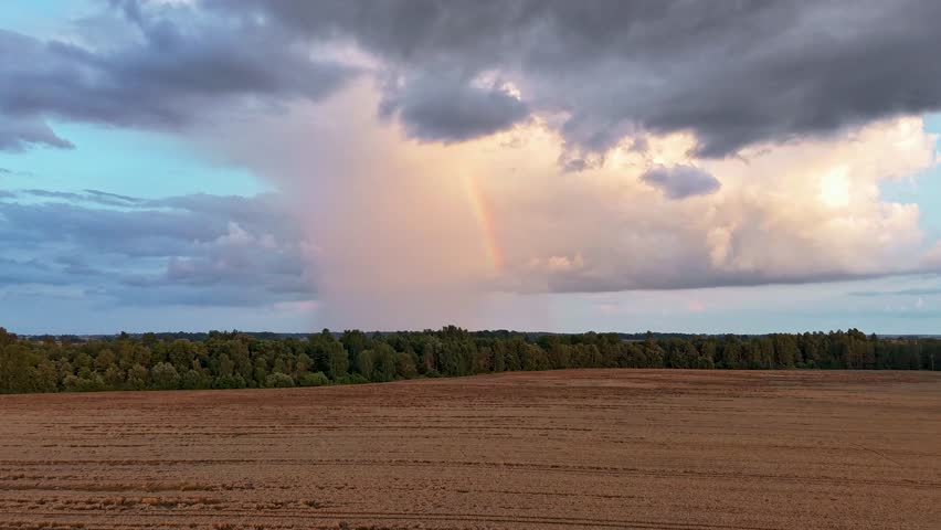 Timelapse of a Grain Field Under Shifting Rain Clouds and a Rainbow as a Storm Builds. Rapid Light Changes and Dramatic Skies Create a Powerful and Visually Striking Natural Scene. Dron Follow Storm