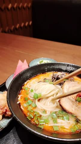 Asian ramen noodles soup with egg, pork and onion. Close-up footage. Chopsticks take noodles.