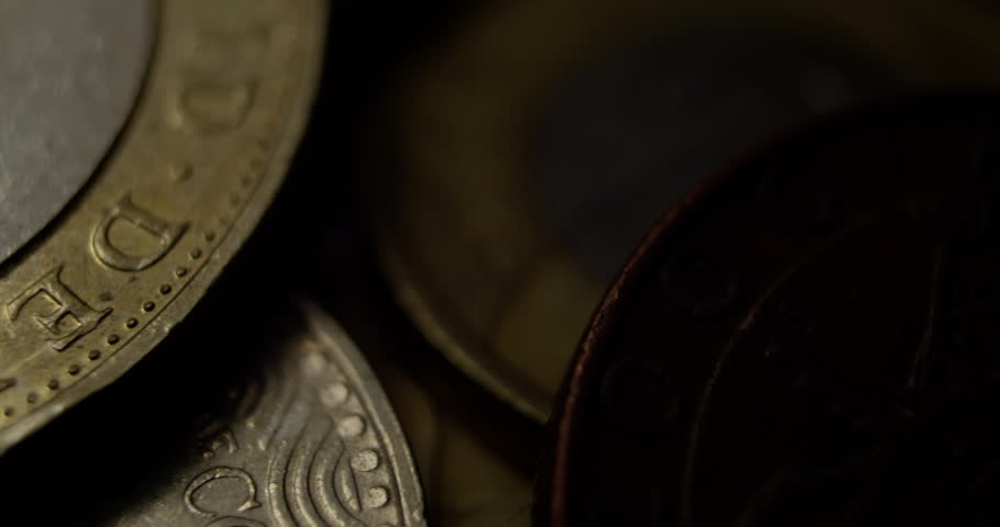 Detailed macro view of a British pound coin showing engraved letters and textures under moody lighting.