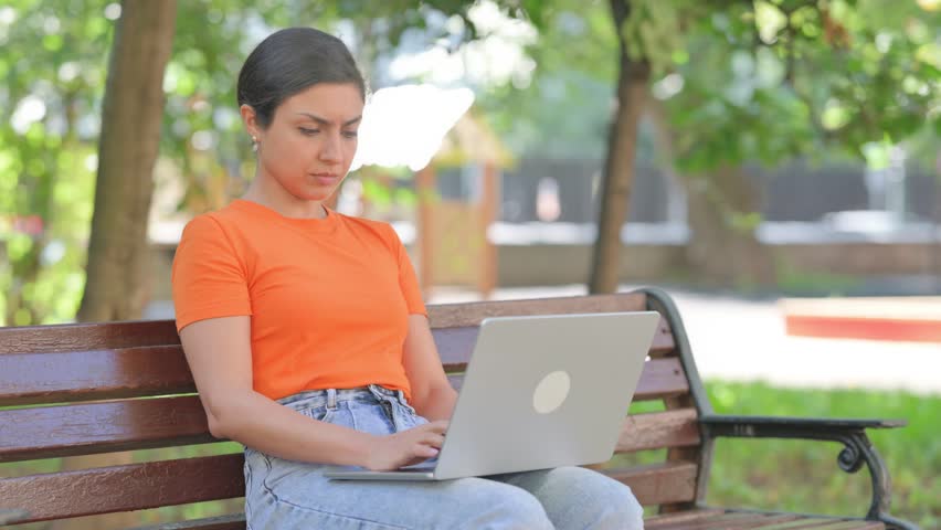 Casual Indian Woman with Back Pain While Using Laptop in Park