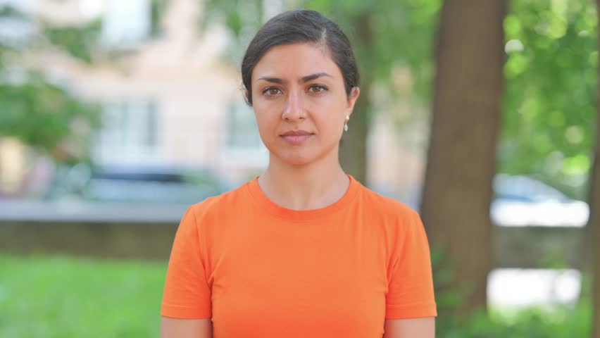 Young Indian Woman with Finger on Lips Outdoors