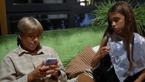 Cheerful, youthful boy and girl relax on vibrant sofa indoors. Sister takes her mobile phone from her brother, as they share casual moment of leisure - Powered by Shutterstock - Get 15% off with code: PIKWIZARD15