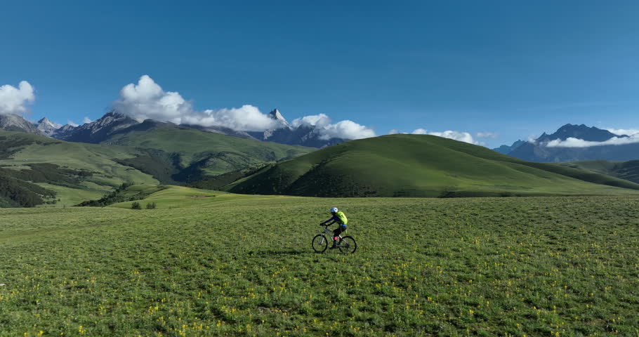 Aerial footage of riding mountain bike in the beautiful flowering grassland and forest mountains, slow motion