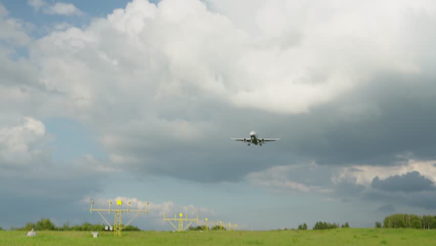 Airplane approaches landing at sunset over calm airport landscape