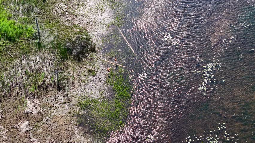 Aerial drone view of rippling water meeting a rocky shoreline with green vegetation in Michigan’s Upper Peninsula.