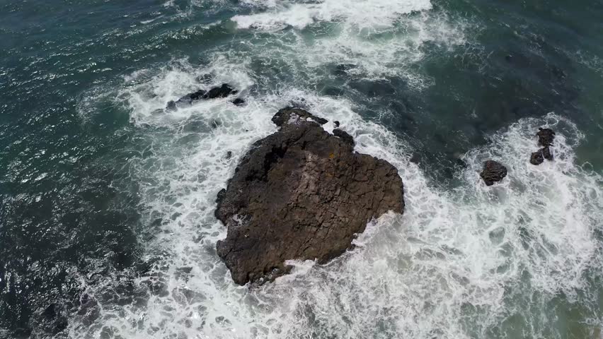 Ocean waves crashing on big rocks at the sandy beach