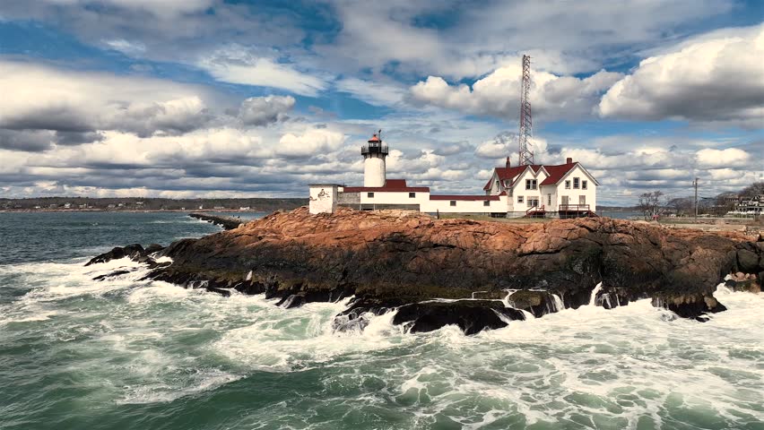 Aerial view of the iconic Eastern Point Light standing proudly against crashing waves and dramatic skies, a beacon of maritime history, Gloucester, Massachusetts, United States.