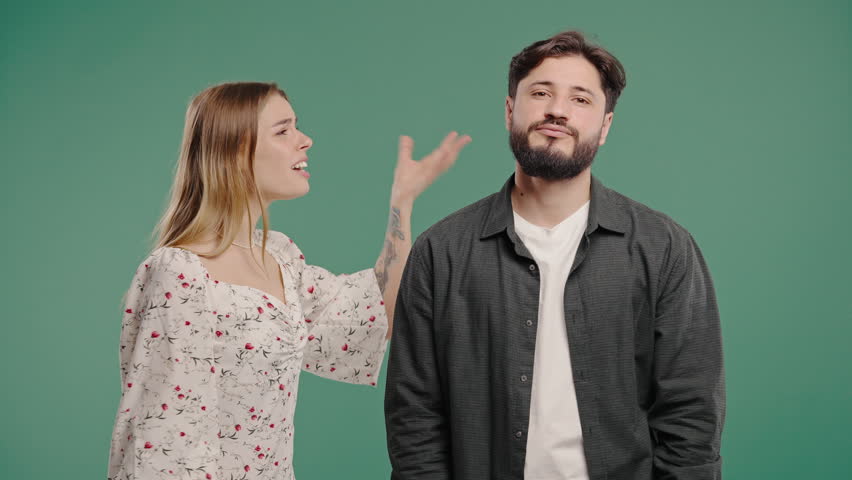 Grumpy blonde woman yelling on man. Irritated boyfriend, young couple on green