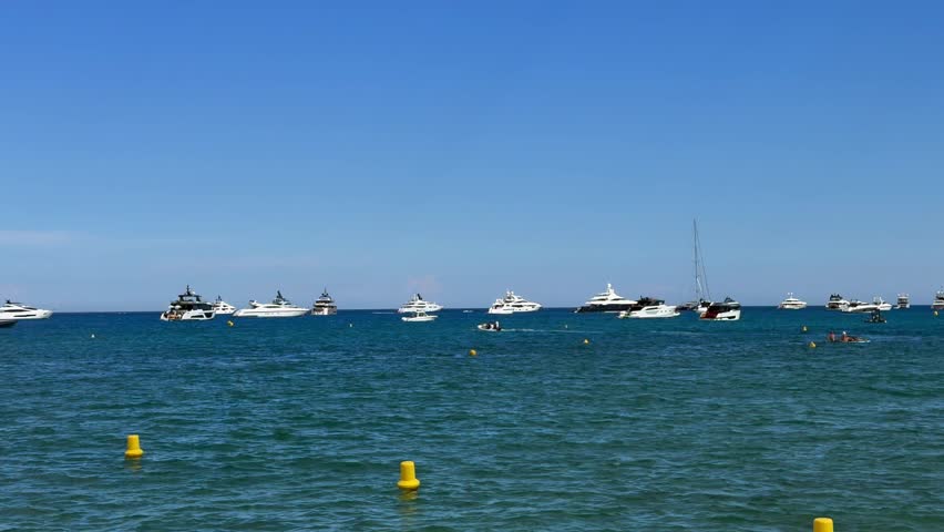 4k video footage, left panning across the Bay at  Pampelonne Beach, located at coastline of Ramatuelle, Côte d’Azur, with many expensive luxury yachts anchored in the Mediterranean Sea