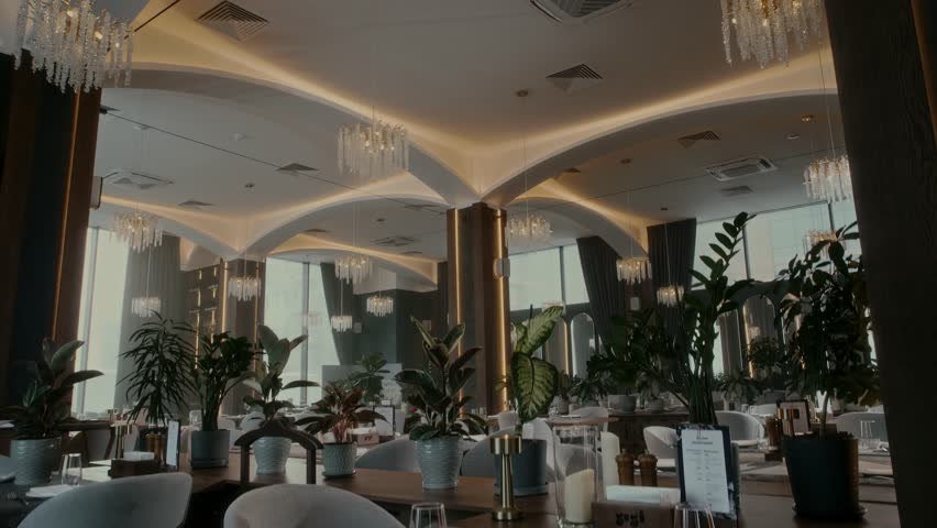 Beautiful designer interior of eco restaurant with many decorative plants and panoramic glazing