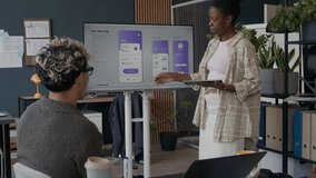 Young adult African American woman presenting UI design of mobile app displayed on screen while collaborating with male colleagues in modern office space - Powered by Shutterstock - Get 15% off with code: PIKWIZARD15