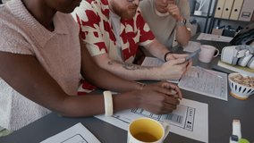 Diverse team of UI designers testing mobile app on smartphone developing user interface collaboratively while sitting at cluttered with papers desk together in modern office space - Powered by Shutterstock - Get 15% off with code: PIKWIZARD15