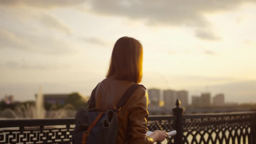 Creative woman on an inspiring sunset walk with a sketchbook, highlighting artistic lifestyle, creativity, and outdoor inspiration.