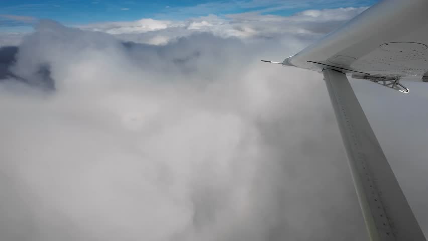 Wingtip of small turboprop airplane flying above the clouds and turning right