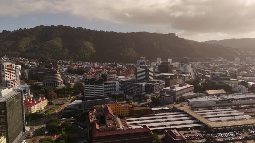 Downtown building of Wellington, New Zealand at Sunset. Aerial wide shot. Cupola and office complex in center near port.