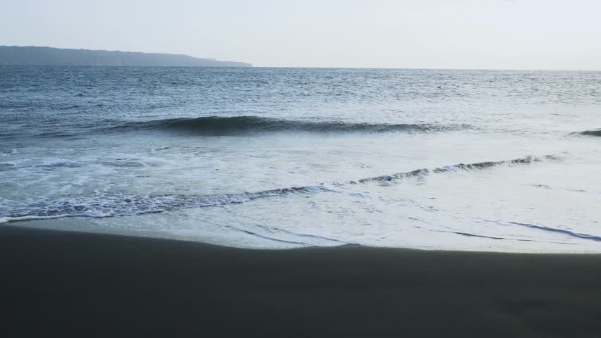waves crashing on Black Sand beach,
Seascape against clear blue sky with rocky island.
Clear and windy horizon and blue sky on a summer day.