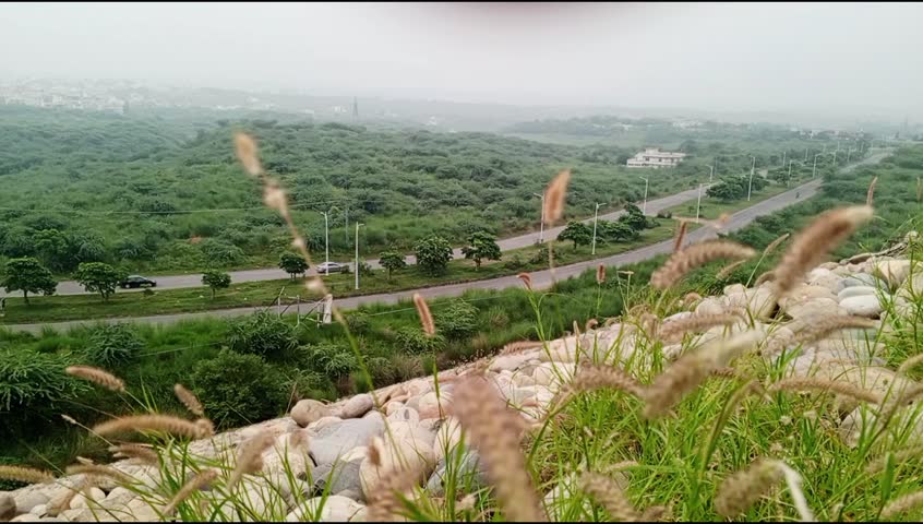 The video features a road winding through a green, hilly landscape with trees and some structures in the background, which is characteristic of the topography around Bhutto park Mirpur Azad Kashmir.
