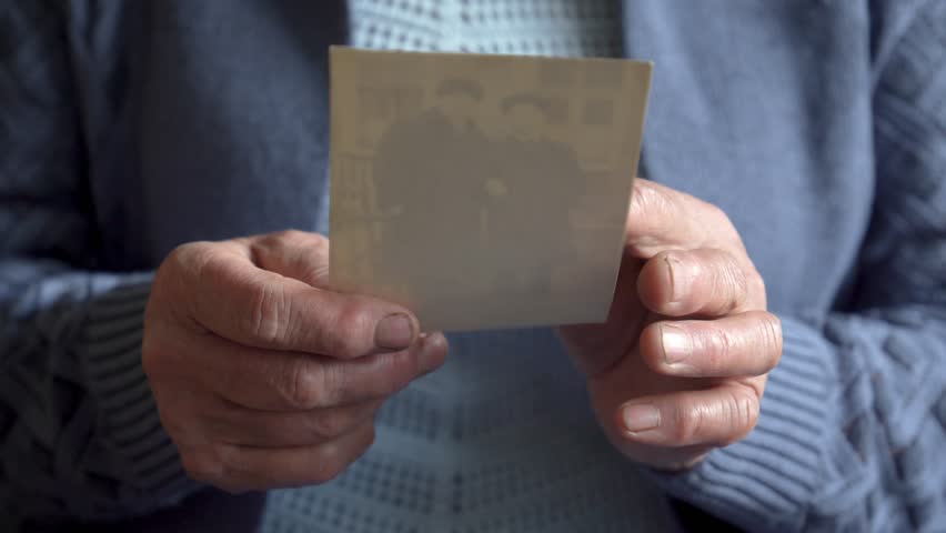 Close up wrinkled hands of old woman gently hold vintage photo. Black white photo with nostalgic touch, evoking cherished memories bygone days. Unrecognizable person. Nursing home life. Old people