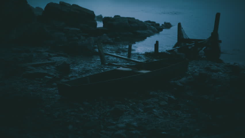 Abandoned wooden boats rest on a rocky shoreline as twilight descends, casting a tranquil blue hue over the water and enhancing the calm atmosphere of the scene.