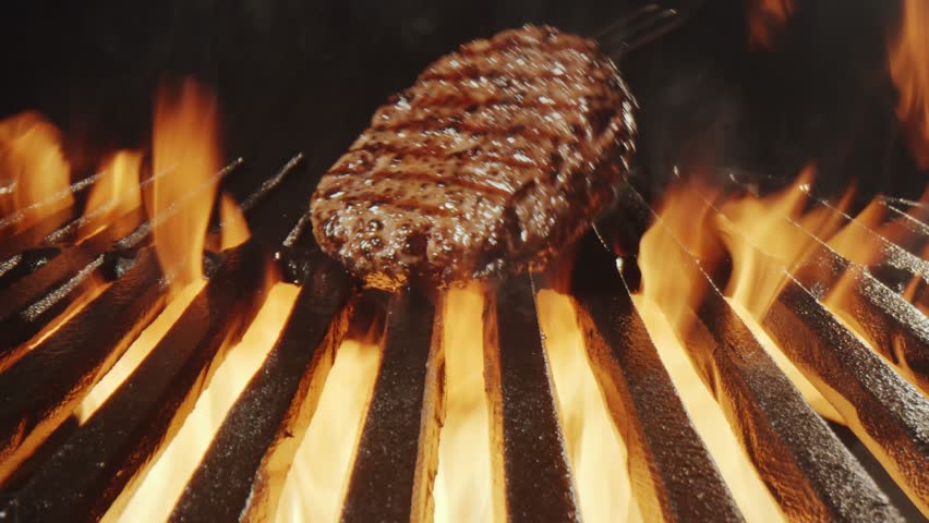 Sizzling burger patties flare up dramatically on hot grill grates, creating a dynamic and mouthwatering culinary scene perfect for food advertising and promotions.