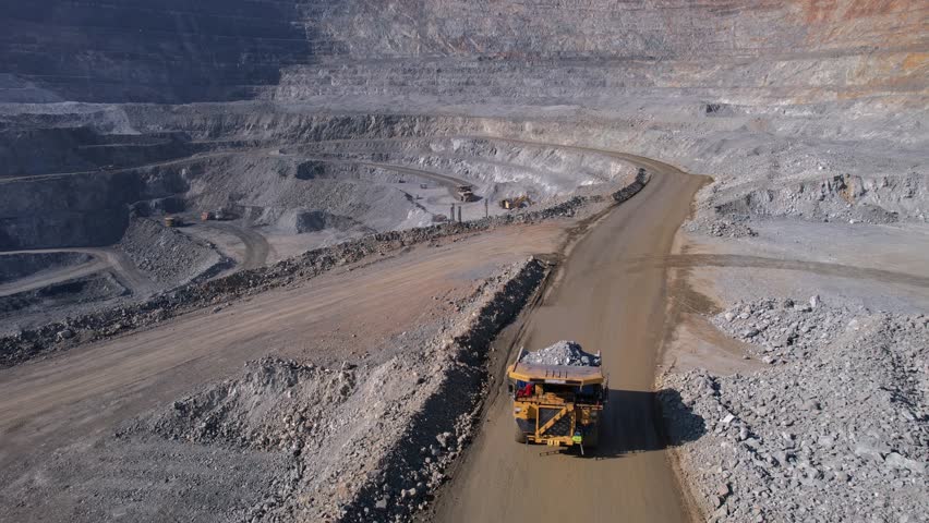 Aerial view mining industry big dump truck transports ore extraction and hauling in open pit mine.