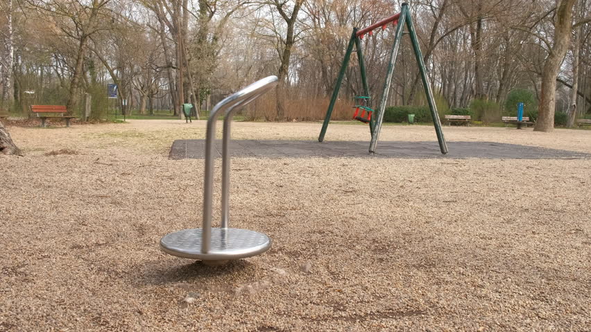 Rotating carousel against forest. A rotating metall carousel between swings in the autumn park