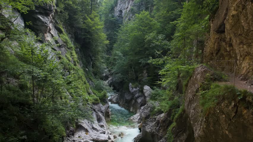 A vibrant emerald river carves through steep limestone cliffs in this dramatic gorge landscape. 