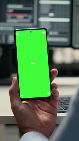 Vertical video Equity analyst using green screen smartphone to reviews quarterly earnings, assessing stock market value. Trader conducts financial analysis using mockup mobile phone to improve