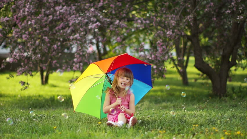 Girl with umbrella sitting on grass
