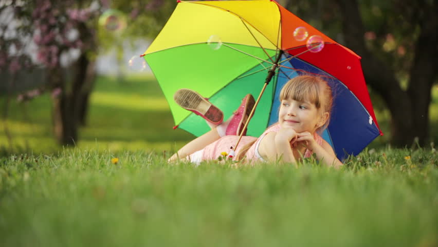 Children lying with umbrella and smiling
