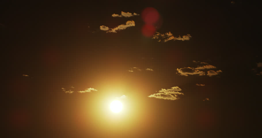 Sun in a late-day summer sky with ragged bunches of cumulus clouds.