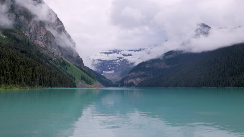 Cloudy day over Lake Louise, turquoise waters reflecting misty Rocky Mountains in Banff National Park