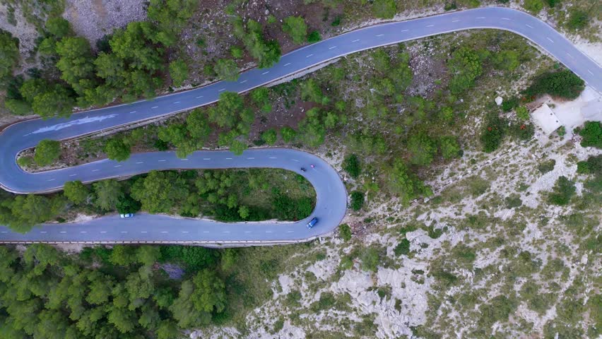 Top down panning aerial view twisting mountain road, automobile journey, steep island highway