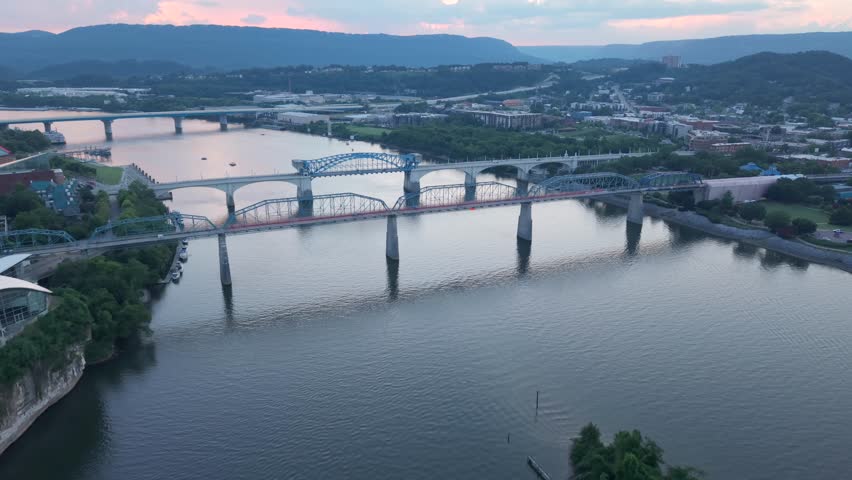 Chief John Ross Bridge and Walnut Street Pedestrian Bridge over the Tennessee River in Chattanooga at dusk - forward dynamic aerial tilt down