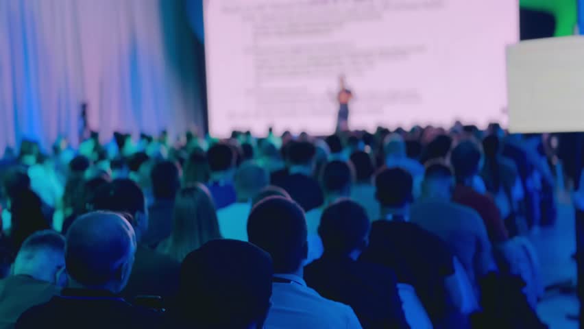 Audience attentively listens to a speaker during conference with professional lighting and atmosphere