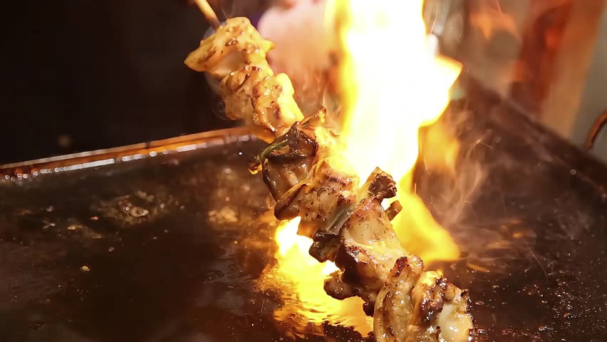Close-up of Japanese yakitori skewer grilled with torch flame. Juicy chicken and vegetables on stick, authentic street food with smoky flavor, perfect for Asian cuisine and food content.