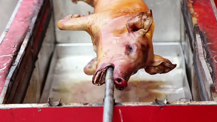 Whole roasted pig on a rotisserie with golden crispy skin, traditional Asian barbecue style, authentic street food cooking, cultural feast and festive cuisine background.