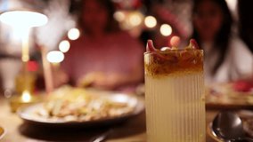 Two women share guacamole dip and tortilla chips at a warmly lit restaurant table, with a passion fruit-infused iced cocktail in sharp foreground focus - Powered by Shutterstock - Get 15% off with code: PIKWIZARD15