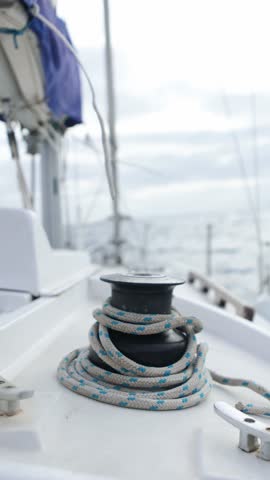 Slow-motion nautical sequence capturing coiling rope winding tightly around sailboat winch, revealing intricate marine equipment details during sailing journey