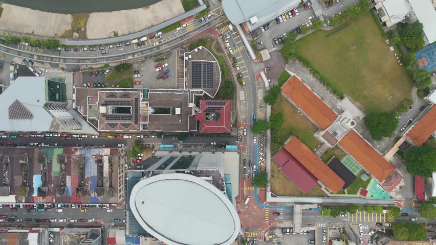 Top-down aerial view of Kuala Lumpur, Malaysia, revealing downtown streets, traffic, river, and urban structures in a bustling city environment.
