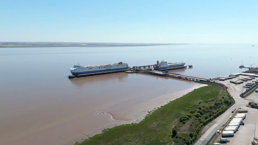 Aerial drone footage of ferries and cargo ships docked at Humber Estuary port with HGVs and industrial buildings in Immingham UK