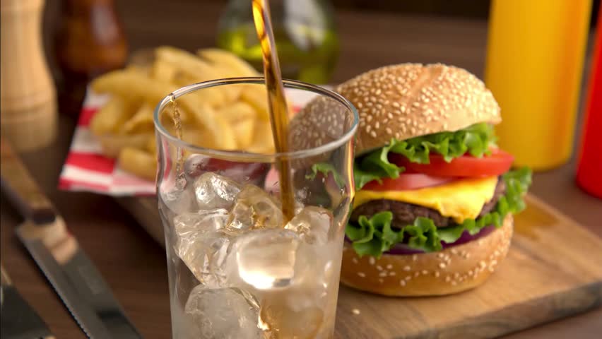 Cola pouring into glass with burger