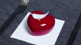 Red, heart shaped mousse cake garnished with delicate white chocolate feather and gold leaf, resting on a doily against a dark textured background, exuding romance and elegance - Powered by Shutterstock - Get 15% off with code: PIKWIZARD15