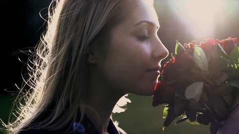 women smelling on red roses. slow motion. sun flare 1080. romantic love background. female single person