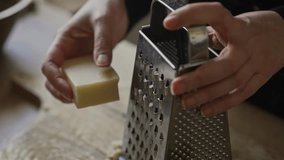 Grating hard cheese on metal kitchen grater. - Powered by Shutterstock - Get 15% off with code: PIKWIZARD15