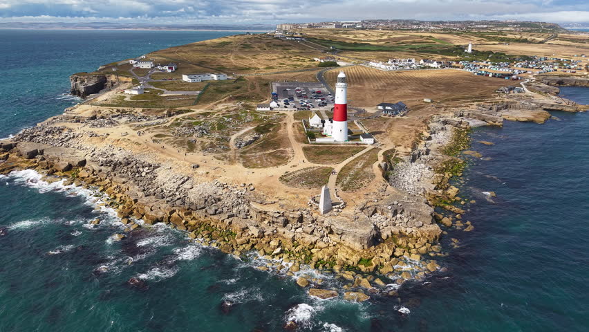 High angle view of Portland Bill lighthouse, peninsula, and rocky English coastline.