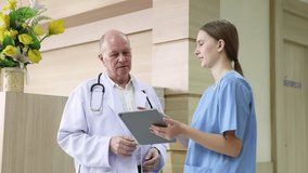 Hospital, healthcare, medical, doctor, nurse using tablet to review patient information, senior male mentoring young student trinee in hallway, technology helps improve teamwork efficiency diagnosis - Powered by Shutterstock - Get 15% off with code: PIKWIZARD15